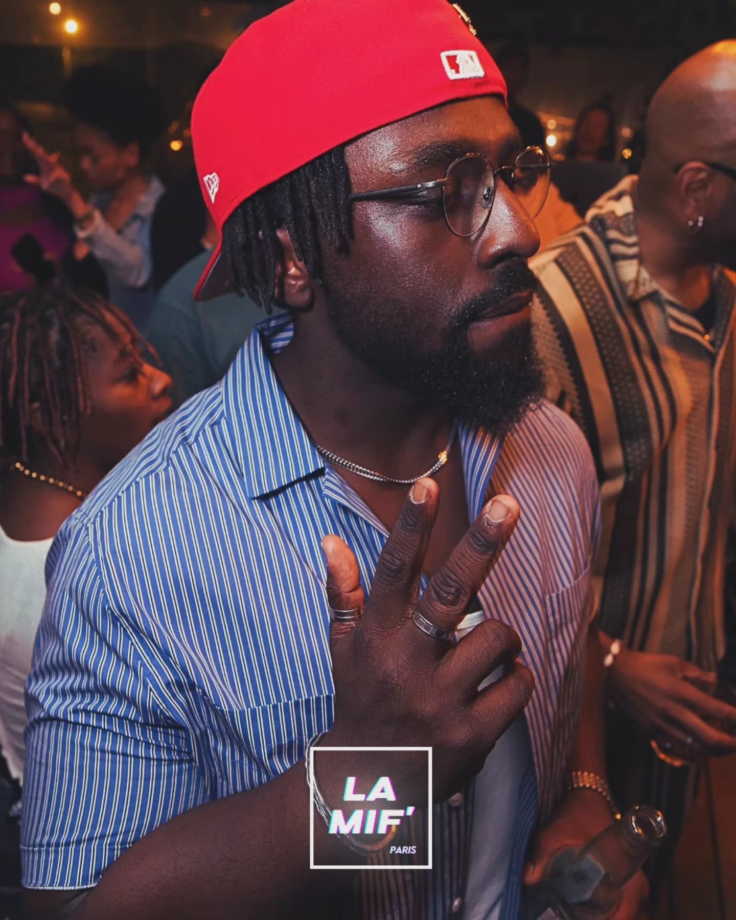 Invité faisant le signe de la paix dans la foule, casquette rouge