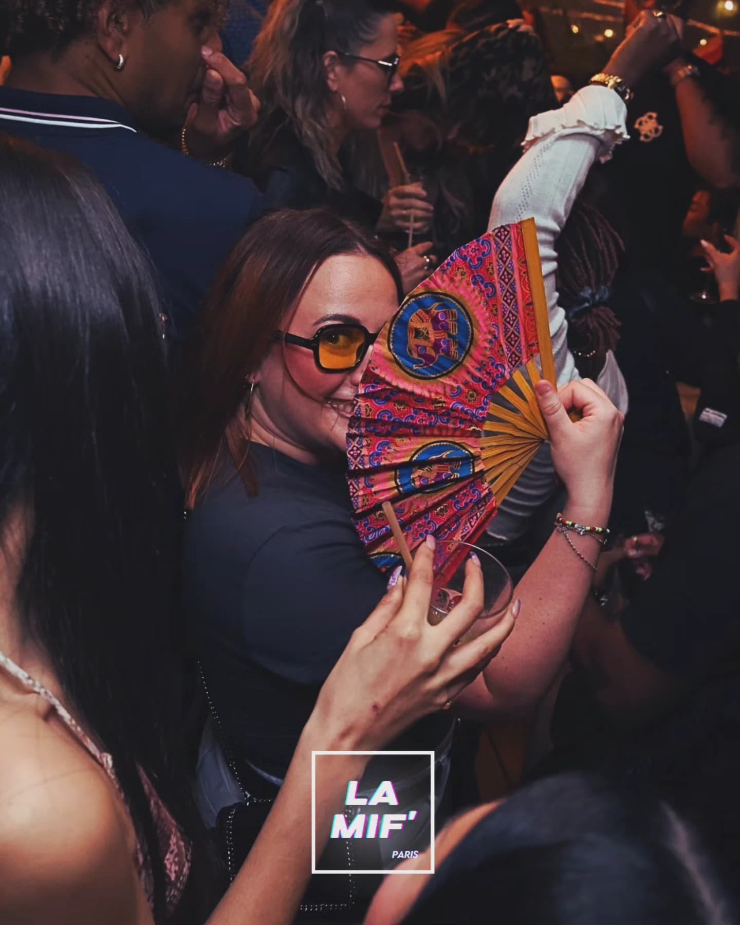 Invitée souriante derrière un éventail coloré